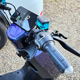 Close-up of a motorcycle handlebar with control panel and blue indicator light.
