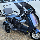 Blue electric scooter with large seat in front of a white van