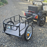 Metal trailer attached to a small vehicle on a gravel surface