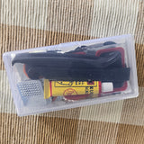 A small clear plastic storage case containing a black shoe or boot with red trim, a yellow tube labeled 'Rubbing Soap', and a small metal brush, placed on a woven beige and brown fabric surface. puncture repair kit for bike