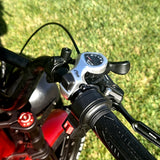 Close-up of motorcycle handlebar with control panel against a grassy background