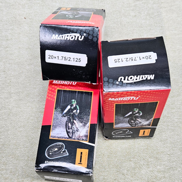 Three Mathotu bicycle tube boxes on a gray surface