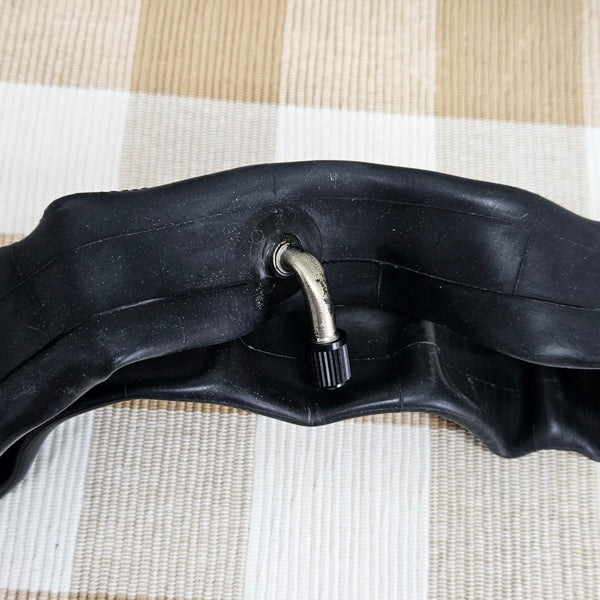 Black bicycle inner tube with valve on a striped fabric background