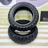 Two black rubber off-road tires stacked on a striped surface, with a branded display board in the background. tyre 10x2.7.00-6.5 solid no punctures