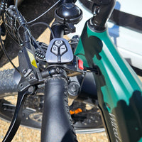 Close-up of a bicycle handlebar with control buttons and brake levers.