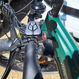Close-up of a bicycle handlebar with control buttons and brake levers.