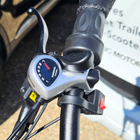Close-up of a motorcycle handlebar with speedometer and control buttons.
