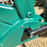 Close-up of a green mechanical component with a black lever on a blurred natural background