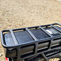 Black motorcycle luggage rack on a gravel surface