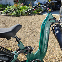 Green electric bike with 'Wired 2 Ride electric BIKE' branding on a gravel surface.