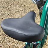 Black bicycle seat on a green bike with gravel background