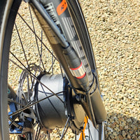 Close-up of a bicycle wheel and suspension fork on a gravel surface