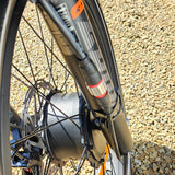 Close-up of a bicycle wheel and suspension fork on a gravel surface