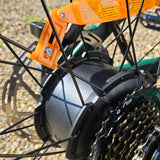 Close-up of a bicycle gear system with an orange reflector on a gravel surface.