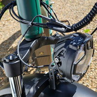 Close-up of a motorcycle headlight and handlebar with a blurred background
